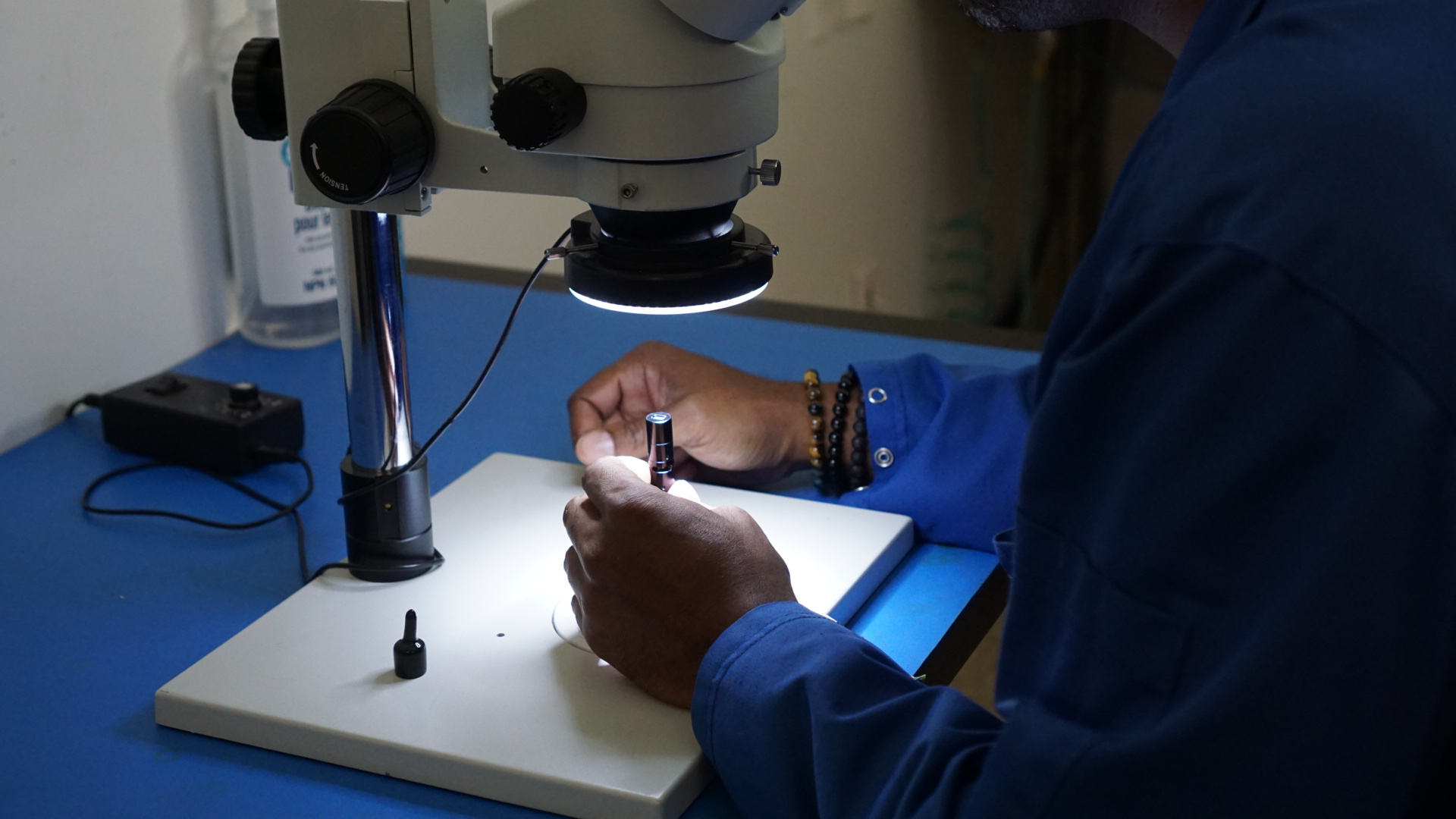 Quality Control Technician intently verifies optical surface quality of Compact Laser using Laboratory Microscope